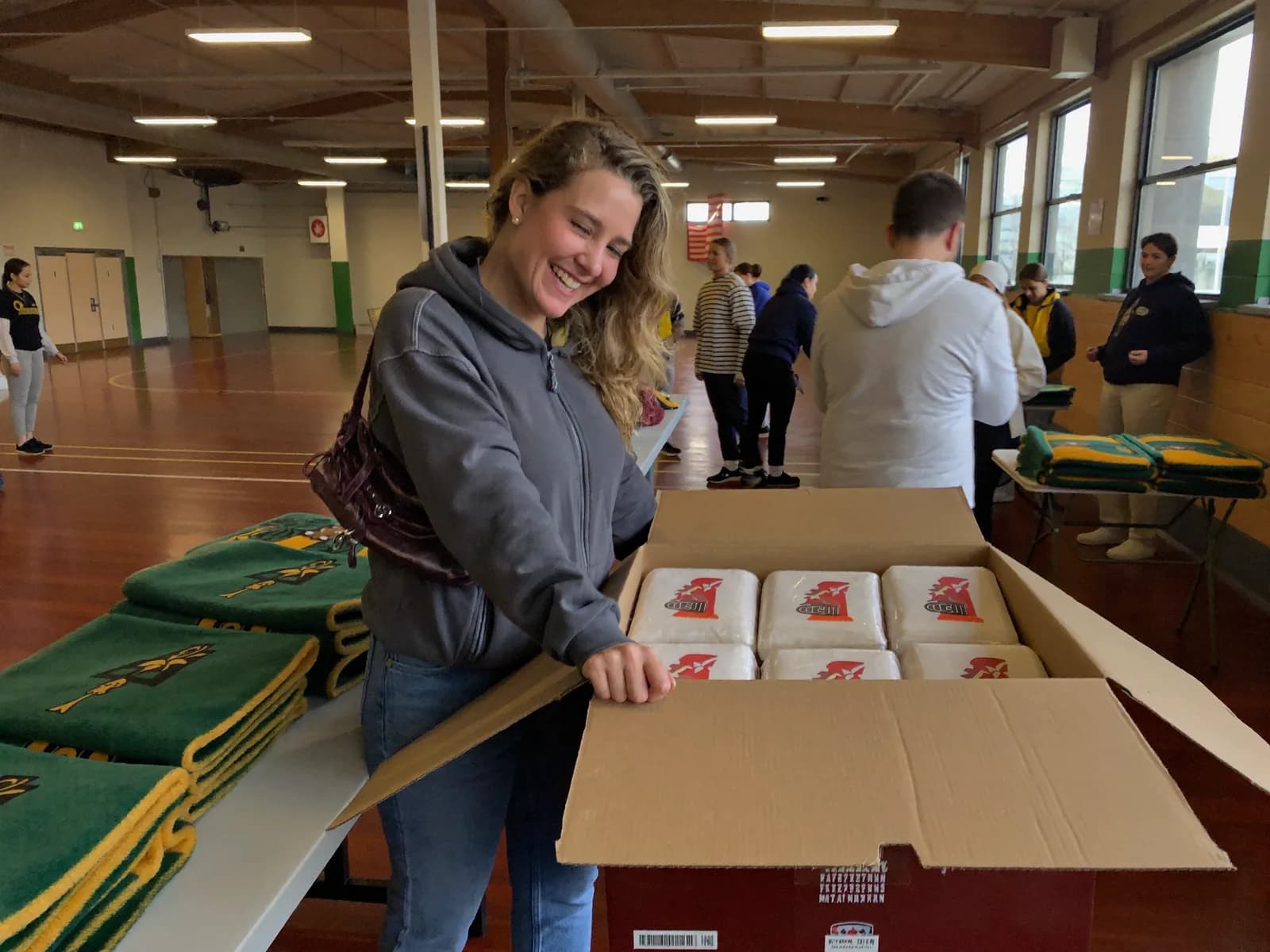 Campaign manager opening the delivery of wrapped blankets in the school gym