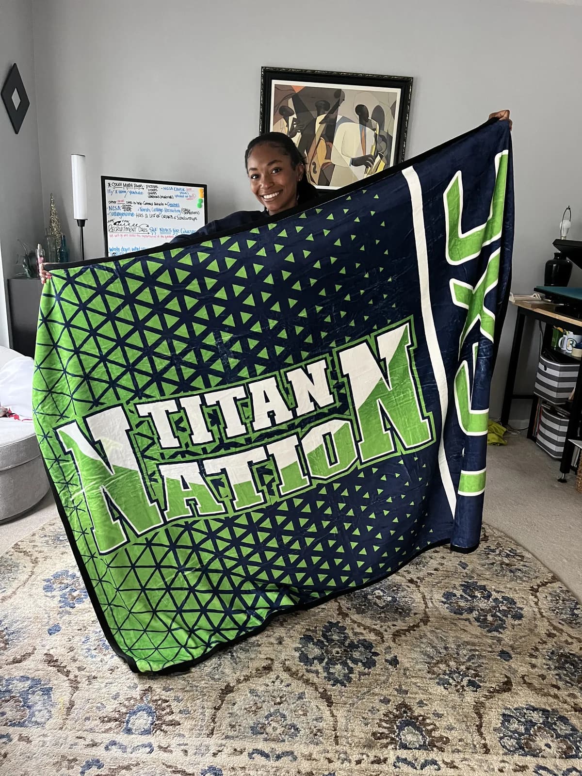 Athlete holding up her school's full-size custom Titan Nation blanket sample at home